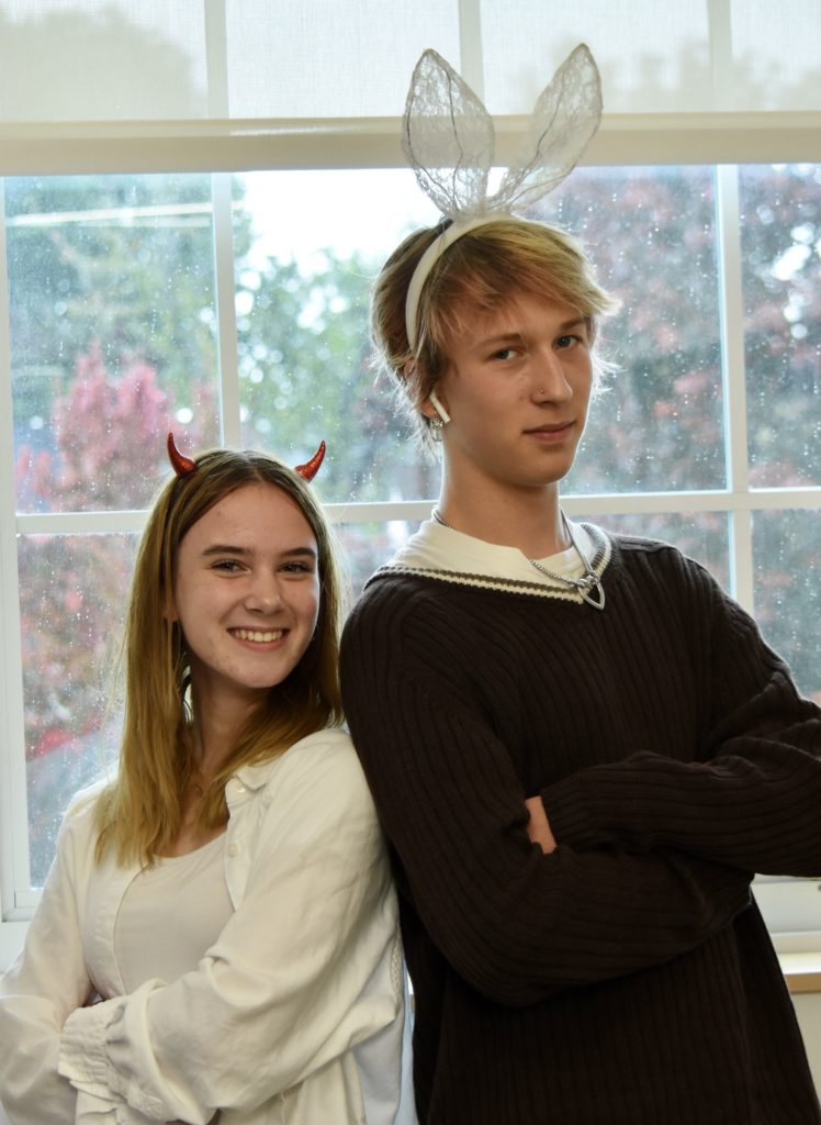 Parnell-Moore and Sears stand next to each other in front of a window. Parnell-Moore wears tiny red horns on her head and a white shirt. Sears wears a black shirt and white, lacy bunny ears. 
