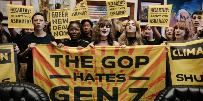 Students stand behind a massive yellow banner saying "The GOP hates Gen Z"