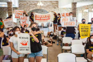 Youth climate activists hold numerous posters with various slogans including, "Green New Deal for Schools" and "We demand pathways to green jobs."