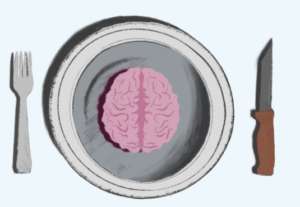 A pink brain sits atop a round plate. A fork is set on the plate's right side and a steak knife is set on the left.