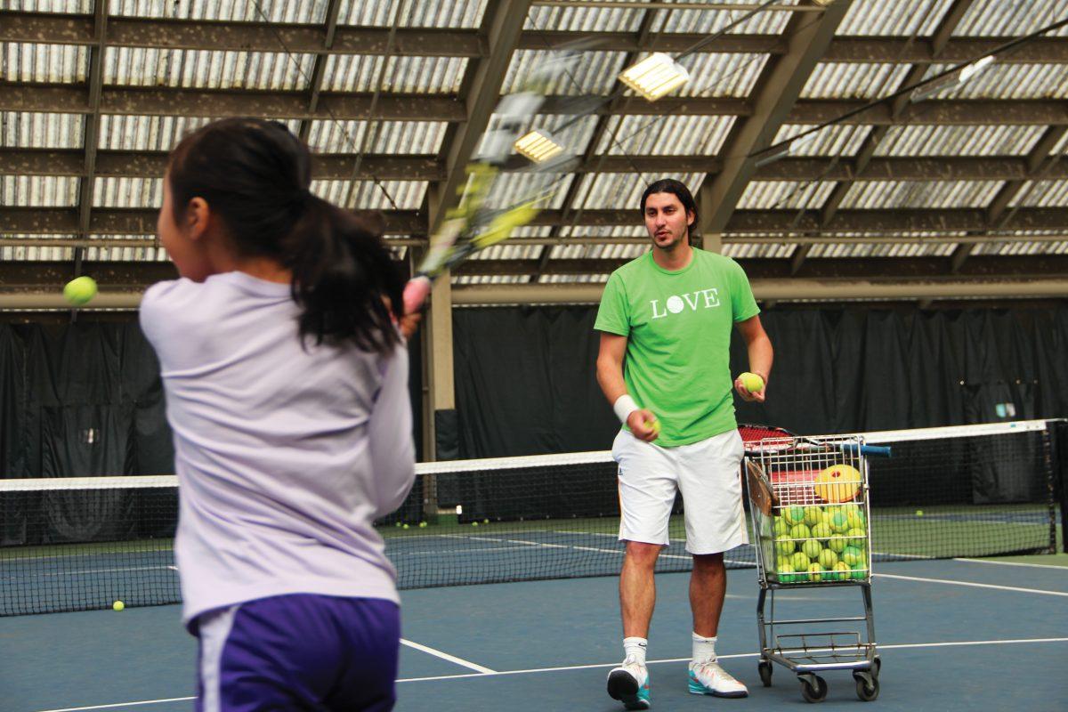 Farhad Roshanaie, new head tennis coach at Grant High School,  tosses balls to star student Lauren Han at the Portland State University courts.