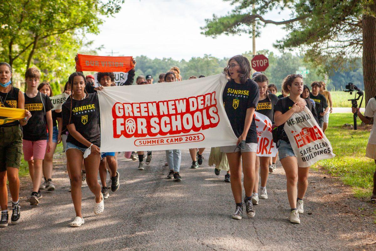 Youth activists march holding a large poster with the words "Green New Deal for Schools."