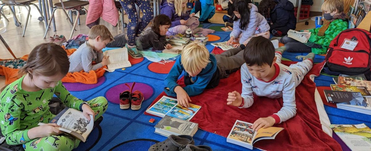 ACCESS students read books on the floor of a classroom.