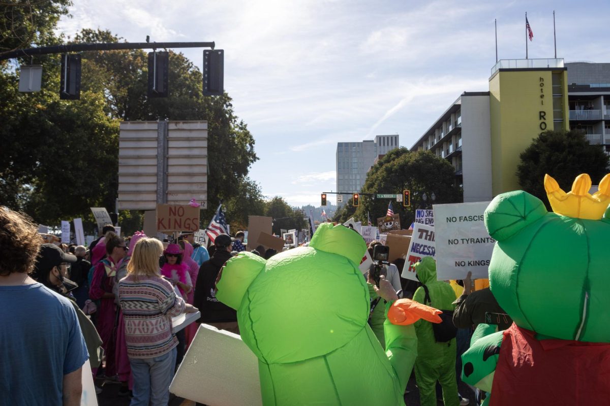 Two protesters wearing inflatable frog outfits march among thousands of others at the Portland No Kings protest on Oct. 19, 2025.